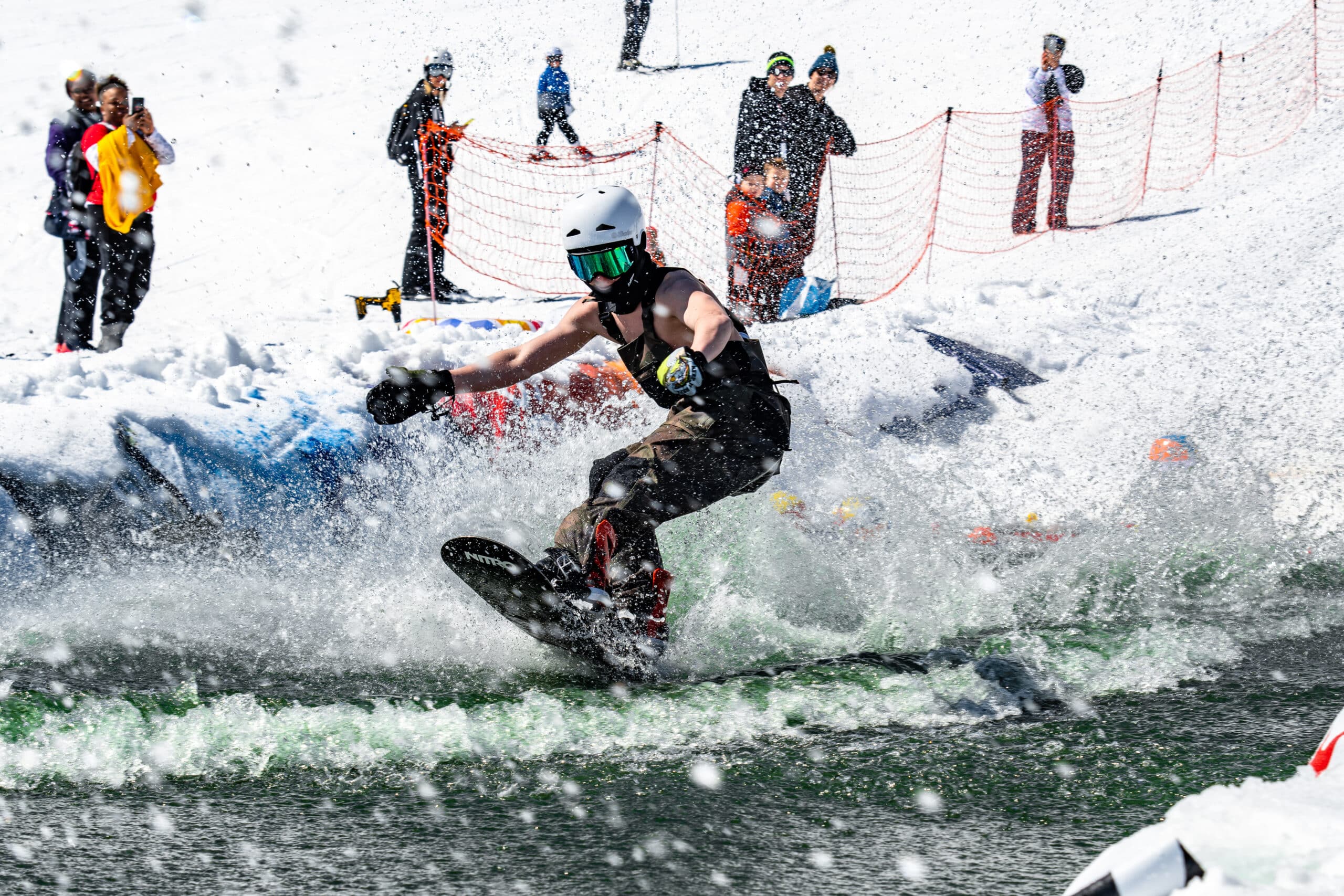 Snowboarder doing a pond skim in the springtime